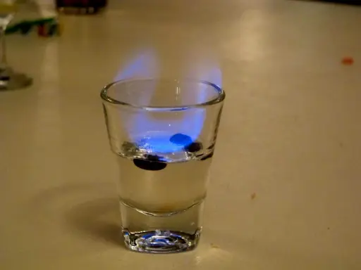 Ein Schnapsglas mit brennendem Sambuca und drei Kaffeebohnen. So schmeckt Sambuca: süß, anisartig und leicht scharf.