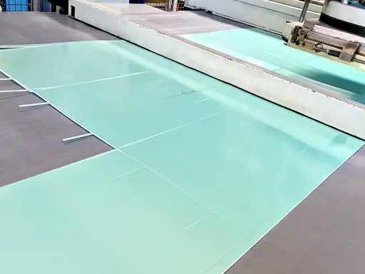 Große, hellgrüne Platten aus PVC-Schaum werden in einer Produktionsanlage zugeschnitten.