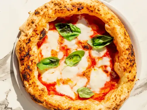 Eine köstliche Pizza Margherita mit geschmolzenem Mozzarella, Tomatensauce und frischem Basilikum. Perfekt für ein einfaches Pizza Margherita Rezept.