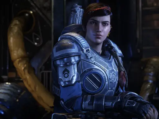 Kait Diaz w zbroi z Gears of War 5, z warkoczem i czerwoną opaską na włosach, w tle industrialne otoczenie.