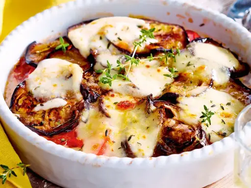 Ein köstlicher Auberginen Tomaten Auflauf mit geschmolzenem Käse und frischen Kräutern, bereit zum Genießen.