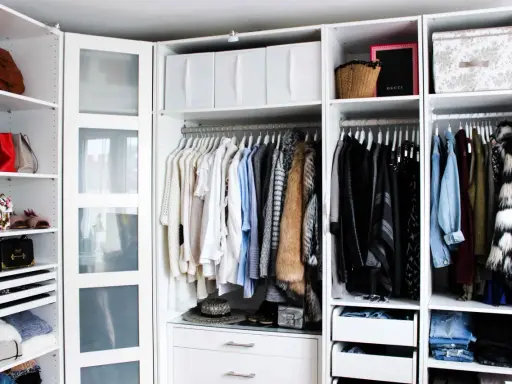 Ordentliche Kleideraufteilung im PAX Kleiderschrank: Hängende Kleidung, Taschen und Boxen sind übersichtlich sortiert.