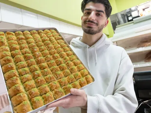 Mann hält eine große Blechschale mit Baklava, bereit für das Zuckerfest.