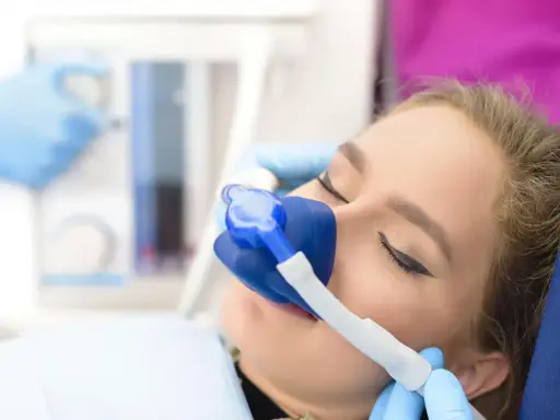 Pacjentka u dentysty z maską do podawania gazu rozweselającego. Zabieg przebiega komfortowo.