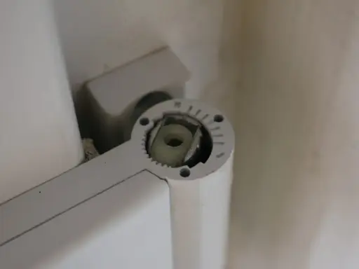 Mécanisme de réglage gond porte, avec une molette crantée et un axe carré pour ajuster la position.