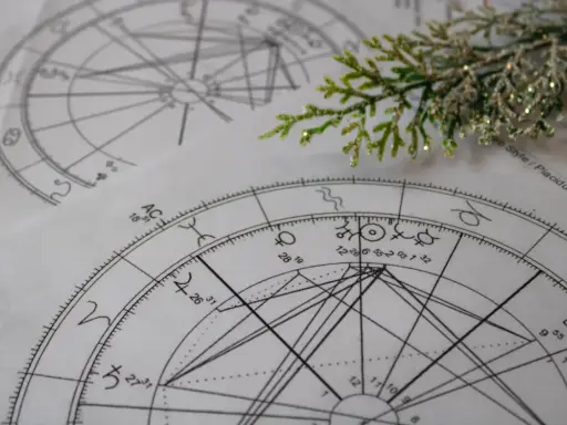 Kosmogram co to? Na papierze widnieją skomplikowane wykresy astrologiczne, pełne symboli planet i znaków zodiaku, przypominające mapę nieba.