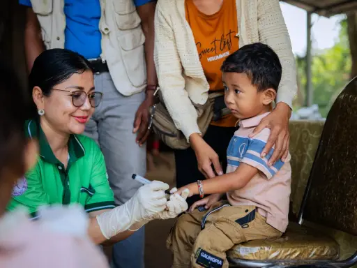 En sjukvårdare med handskar markerar ett barns finger efter vaccination i Kambodja.