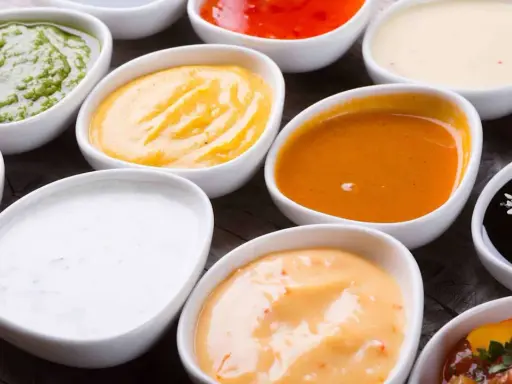 Assortiment de sauces pour raclette : verte, jaune, orange, blanche, rouge, noire. Un délice pour accompagner votre fromage fondu.