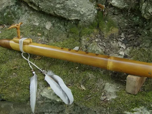 Flûte en bambou, ornée d'un oiseau sculpté et de plumes, prête à fabriquer des mélodies naturelles.