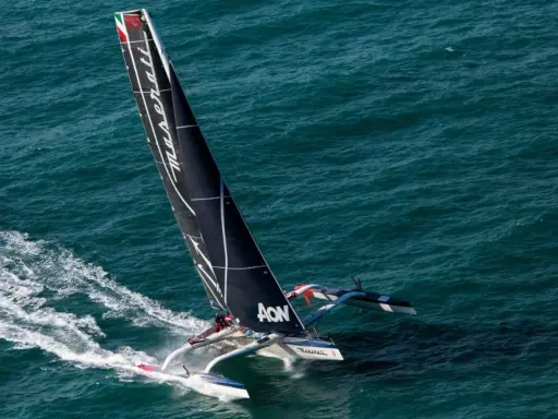 Le trimaran Maserati, skippé par Giovanni Soldini, fend les vagues bleues, laissant une traînée d'écume.