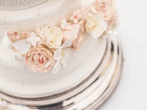 Elegancki tort na 150 osób, ozdobiony delikatnymi koronkami i pastelowymi kwiatami z masy cukrowej. Idealny na wielkie przyjęcie.