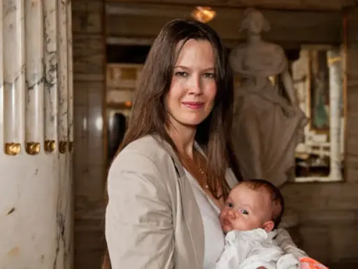 Elin Klinga med sitt barn. En vacker mamma med sitt nyfödda barn i famnen, omgivna av klassisk arkitektur.