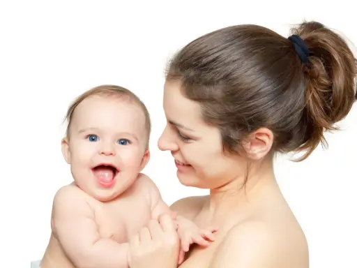Uśmiechnięta mama tuli radosne dziecko. Pomimo nerwowa atmosfera w domu, dziecko rozjaśnia wszystko swoim uśmiechem.