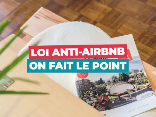 Un magazine sur la **loi Airbnb** est posé sur un meuble en bois. Le titre "Loi anti-Airbnb, on fait le point" est bien visible.