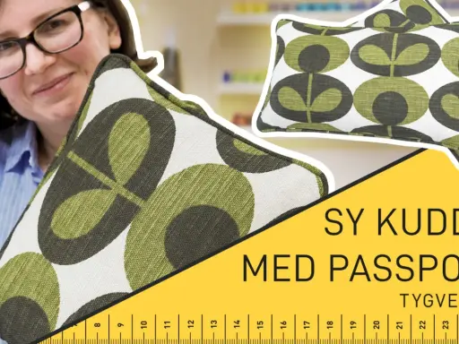Kvinna med glasögon håller ett kuddfodral med grönt mönster. Texten "Sy kudde med passpoal!" syns.