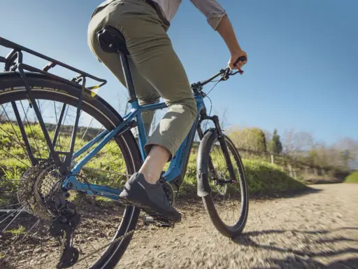 Fahrer auf einem blauen E-Bike mit Shimano Linkglide Schaltung genießt eine Fahrt auf einem Feldweg.