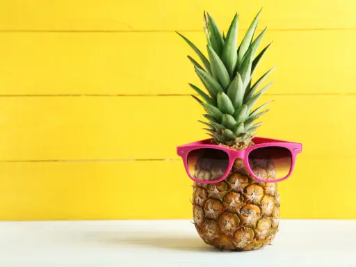 Ananas w okularach przeciwsłonecznych na żółtym tle. Czy wiesz, jaki ananas indeks glikemiczny ma dla Twojej diety?