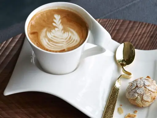 Ein Latte Macchiato mit schönem Milchschaum-Muster und ein Mandelgebäck, perfekt zum wiener Zubereiten.