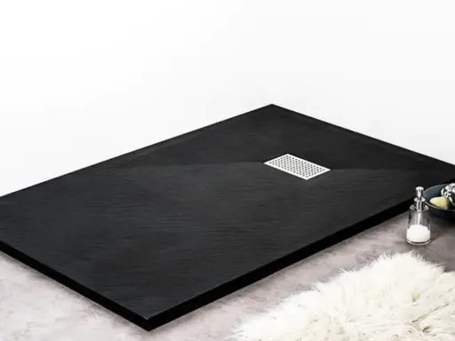 Receveur de douche noir texturé, avec une grille d'évacuation chromée. Un savon et une serviette sont posés sur le bord.