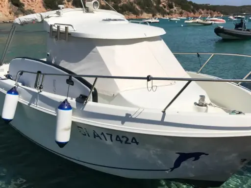 Bateau blanc à quai, avec pare-battages bleus et blancs. Le numéro d'immatriculation est visible, ainsi qu'un dauphin peint sur la coque. Fiche technique du Arvor 20.