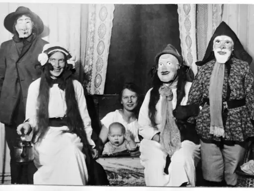 En familj klädd i masker och dräkter, kanske en del av julens historia, poserar för ett fotografi. En bebis sitter i förgrunden.