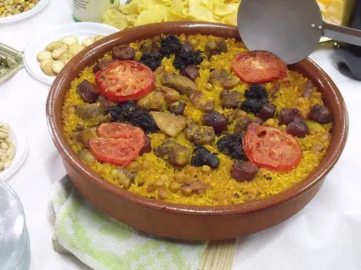 Un delicioso arroz al horno en cazuela de barro, con trozos de carne, chorizo, garbanzos y rodajas de tomate.