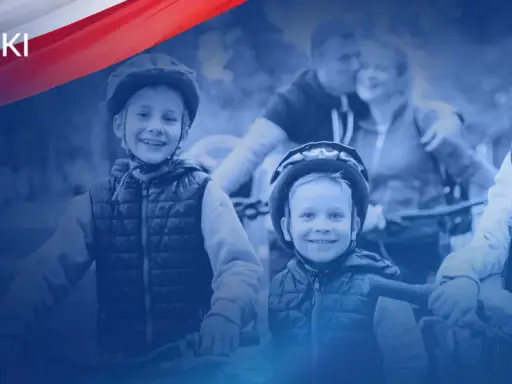 Uśmiechnięte dzieci w kaskach na rowerach, wspierane przez rodziców. Polski Ład to wsparcie dla rodzin.