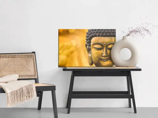 Buddha-tavla med matt material bredvid en stol med pläd och ett bord med en vas.