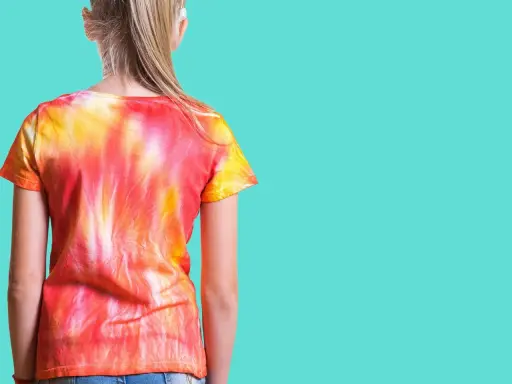 Dziewczynka w koszulce tie dye w odcieniach czerwieni i żółci.