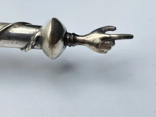 Manico in argento 325, cosa significa? Un dettaglio di un oggetto con una mano che indica.