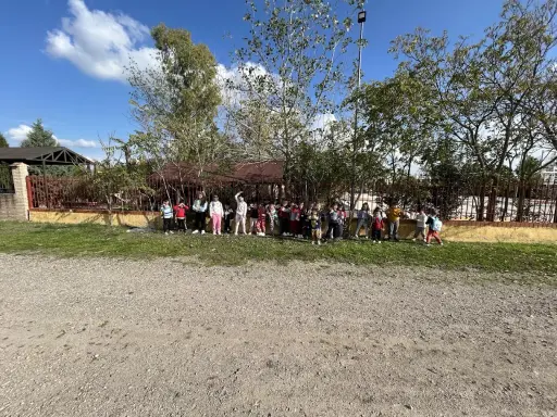Niños y niñas posan en la granja escuela La Chopera, disfrutando de un día soleado rodeados de árboles y vegetación.