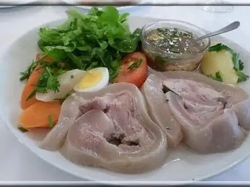Tête de veau en cocotte, servie avec des légumes, un œuf dur et une sauce vinaigrette. Un plat traditionnel savoureux.