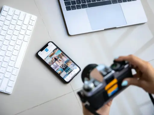 Aparat fotograficzny służy do uwieczniania chwil. Obok klawiatury, telefonu z Instagramem i laptopa, jest gotowy do pracy.