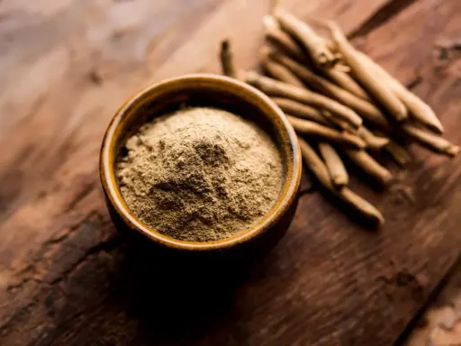 Proszek z korzenia ashwagandhy w miseczce obok gałązek. Naturalne wsparcie dla spokojnego snu.