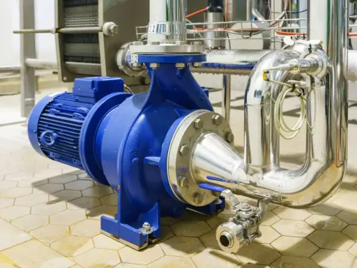 Pompe à eau industrielle bleue, connectée à des tuyaux en acier inoxydable. Un système essentiel pour gérer la pression eau maison.