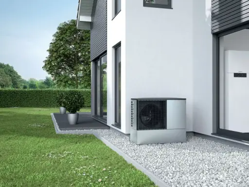 Unità esterna per riscaldamento con condizionatore, posizionata accanto a una casa moderna con giardino curato.