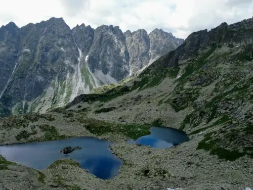 Dwa górskie jeziora odbijające niebo w sercu słowackich Tatr, otoczone skalistymi zboczami i zielenią.