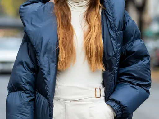 Outfit maestra asilo: piumino blu, dolcevita beige e pantaloni chiari con cintura.