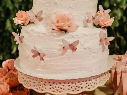 Gâteau à étages décoré de roses et de papillons, recouvert d'une délicate crème au beurre.