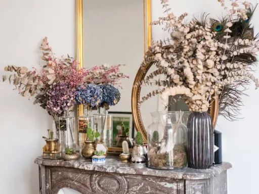 Des idées pour que faire avec des hortensias séchés : bouquets, décorations avec des plumes de paon et des cactus sur une cheminée en marbre.