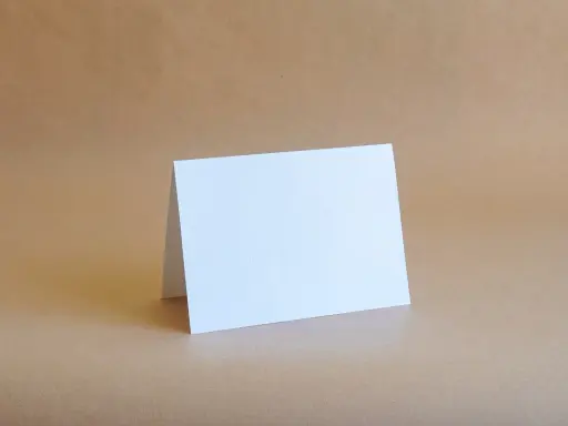 Biała kartka formatu B6 (12,5 x 17,6 cm) złożona na pół, gotowa na Twoje życzenia.