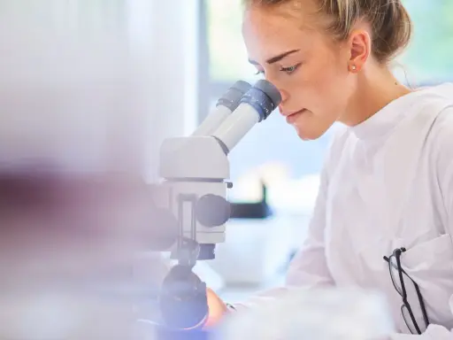 Ricerca scientifica per capire cos'è il sarcoma. Giovane scienziata al microscopio.