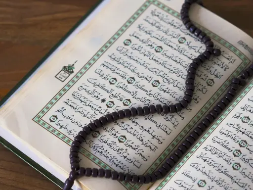 Ein offener Koran mit einer Gebetskette liegt auf einem Holztisch. Der Koran ist ein heiliges Buch im Islam, das von Muslimen auf der ganzen Welt verehrt wird. Israel ist ein Land im Nahen Osten, das eine reiche Geschichte und eine vielfältige Bevölker...