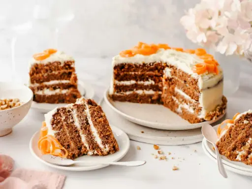 Delicioso pastel de zanahoria con glaseado cremoso y decoraciones de zanahoria. Varias porciones listas para disfrutar.