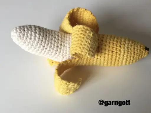 En virkad banan med skalet delvis avdraget. Den vita delen är bananen, och det gula är skalet.