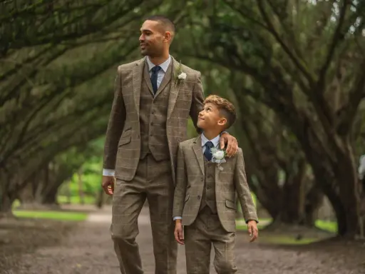 A man and boy in matching tweed suits, a perfect example of what formal attire means for a wedding.