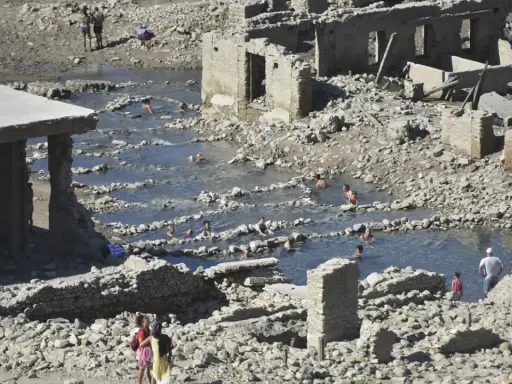 Ruinas de las termas de Yesa, con gente bañándose en las piscinas naturales formadas entre los escombros.