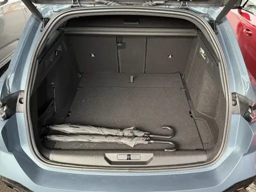 Maletero abierto de un Peugeot 308 SW con dos paraguas negros. Las medidas del maletero son amplias para equipaje.