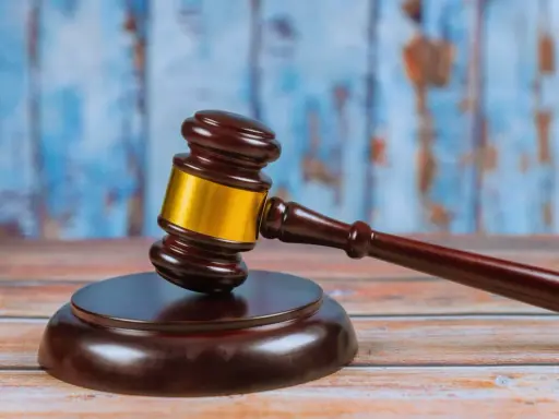 Młotek sędziowski na drewnianym stole, symbolizujący ważną decyzję prawną, jak wniosek o pozbawienie władzy rodzicielskiej.