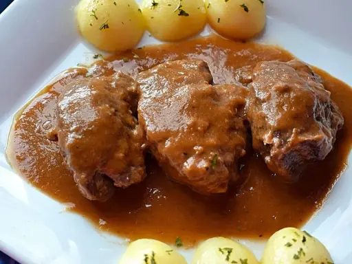 Carrilleras al vino tinto, tiernas y jugosas, bañadas en una rica salsa, acompañadas de patatas cocidas.